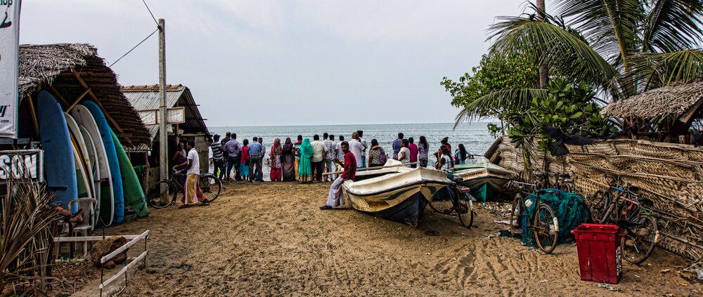 A crowd gathers to watch family members swimming in the waves at Arugam Bay