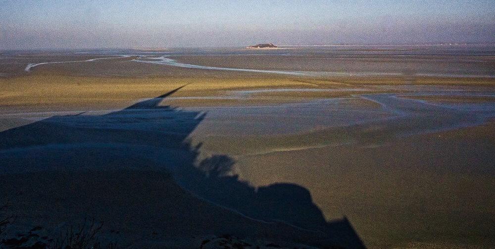 Visiting Mont-St-Michel the shadow of the church across the sand at low tide