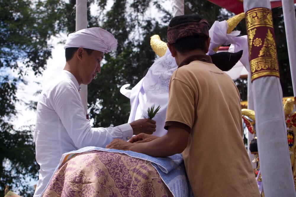 Balinese cremation ceremony: the priest in white blessing the remains