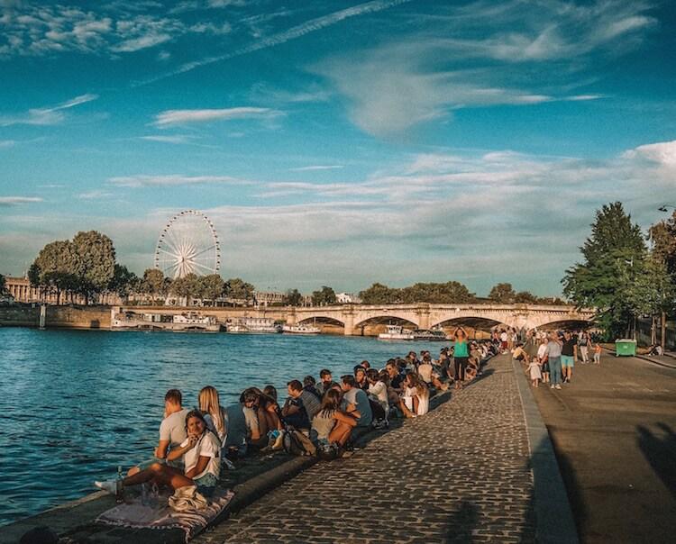 Explore Paris: rows of people sitting along the Seine