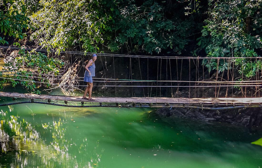 Contact: Dreamer at heart crossing a rope bridge over green water
