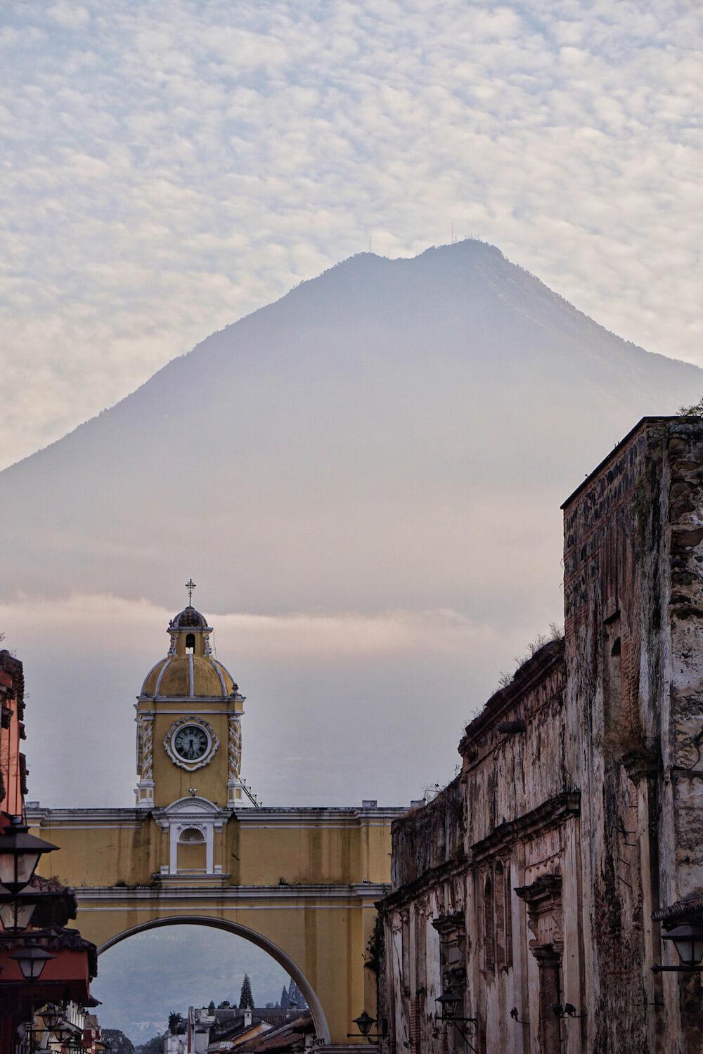 Antigua Guatemala- the yellow archway and clock tower span the street with the volcano in the background