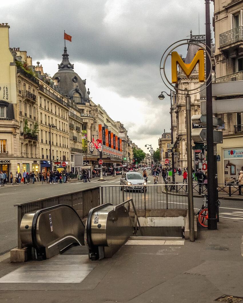 Yellow M showing the Paris metro entrance; escalator down 
