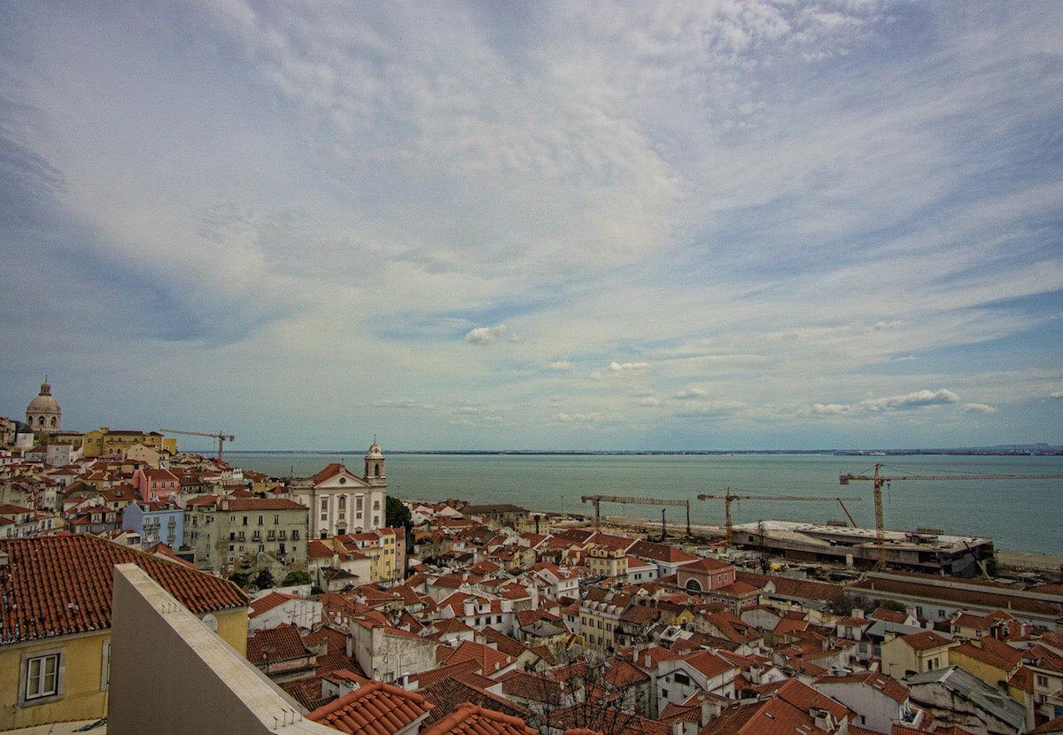 Welcome to Portugal| red clay rooftops spread out to the ocean with a white church in the distance