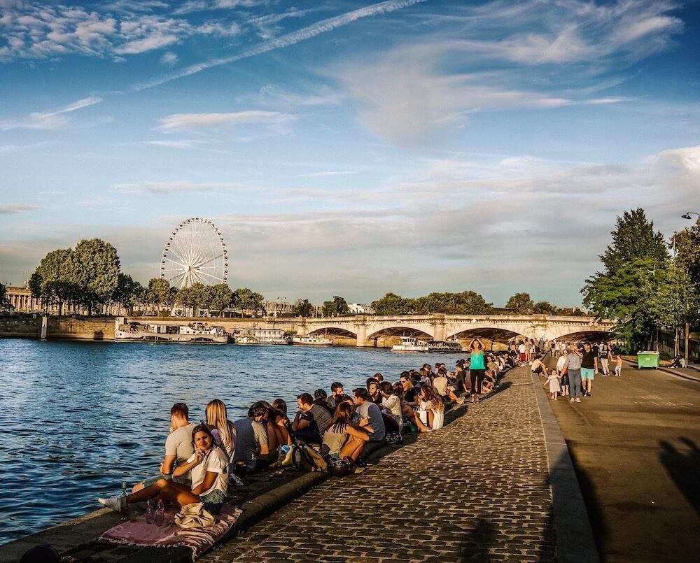 Parisians sitting along the seine on a warm evening - one of the best Paris Experiences 