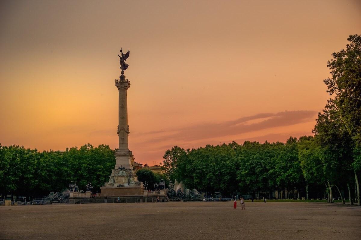 Visit Bordeaux| Place des Quiconces the column with the bird lady on top in the sunset