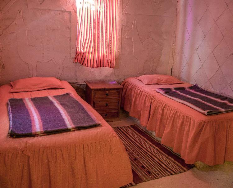 Twin beds with orange bedspreads, orange curtain, salt walls