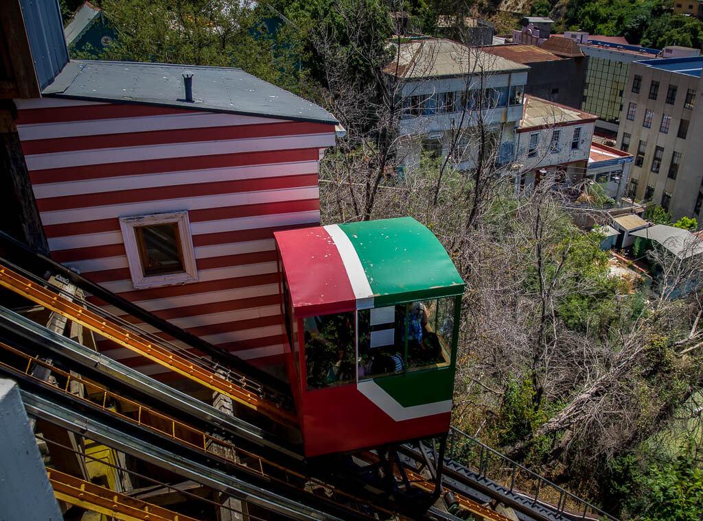 small red, white and green elevator box riding up the steep rails