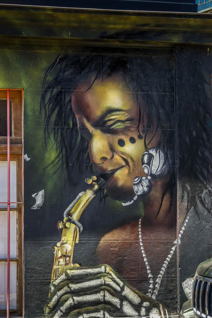 Things to do in Valparaiso: street art of a man playing an instrument, eyes closed, skeletal hand