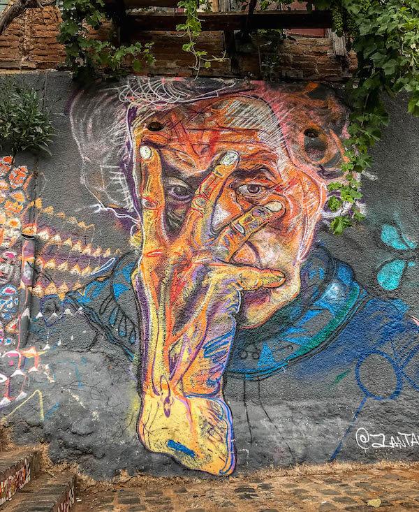 One of the things to do in Valparaiso, Chile is admire the street art: this old woman is resting her face in her hand, eyes peeking out between fingers