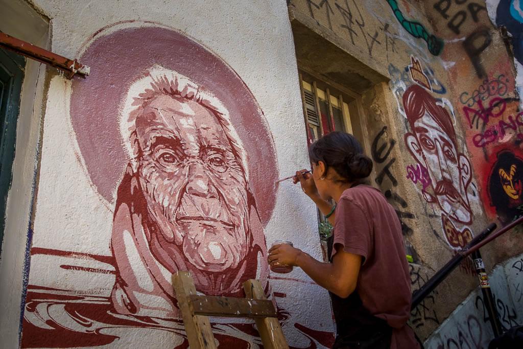 Things to do in Valparaiso: Artist is at working painting an old mans face in terra cotta coloured paint
