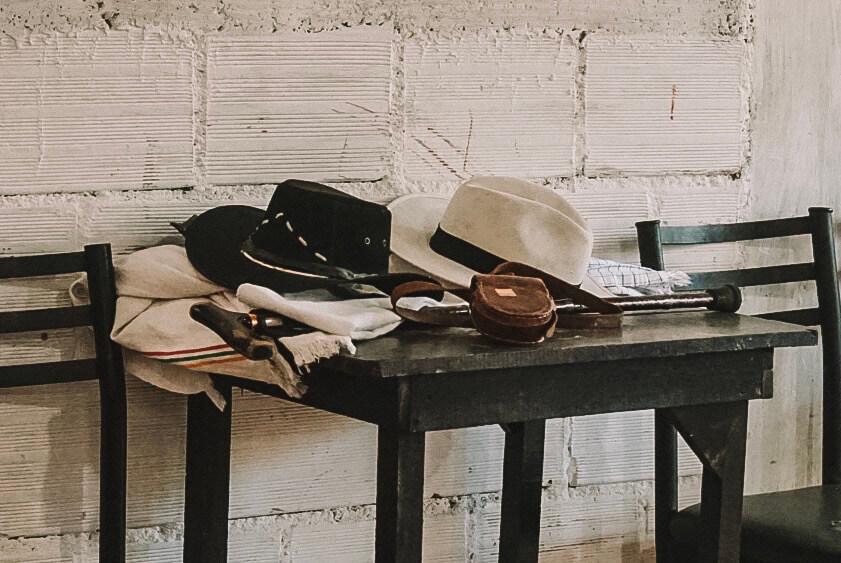 Two cowboy hats, a poncho and a leather money pouch wait on a table while tejo is played