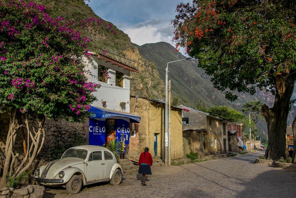 Solo travel as a woman: A street in Ollantaytambo with a Volkswagen bug and a woman walking 