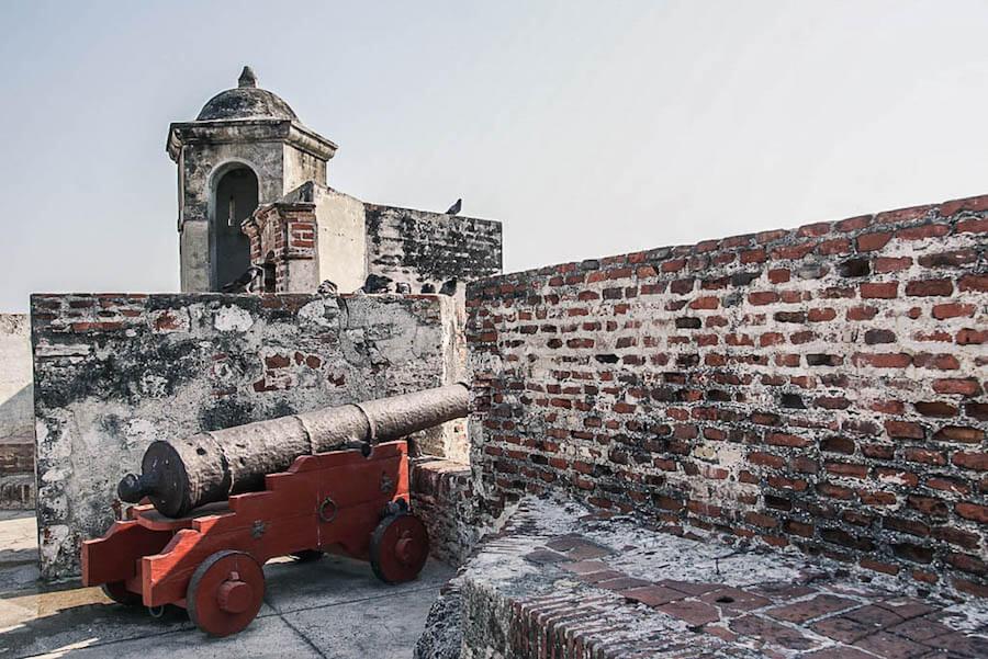 Things to do in Cartagena: One of the 68 cannons sitting on its red base positioned to shoot through the fortified wall