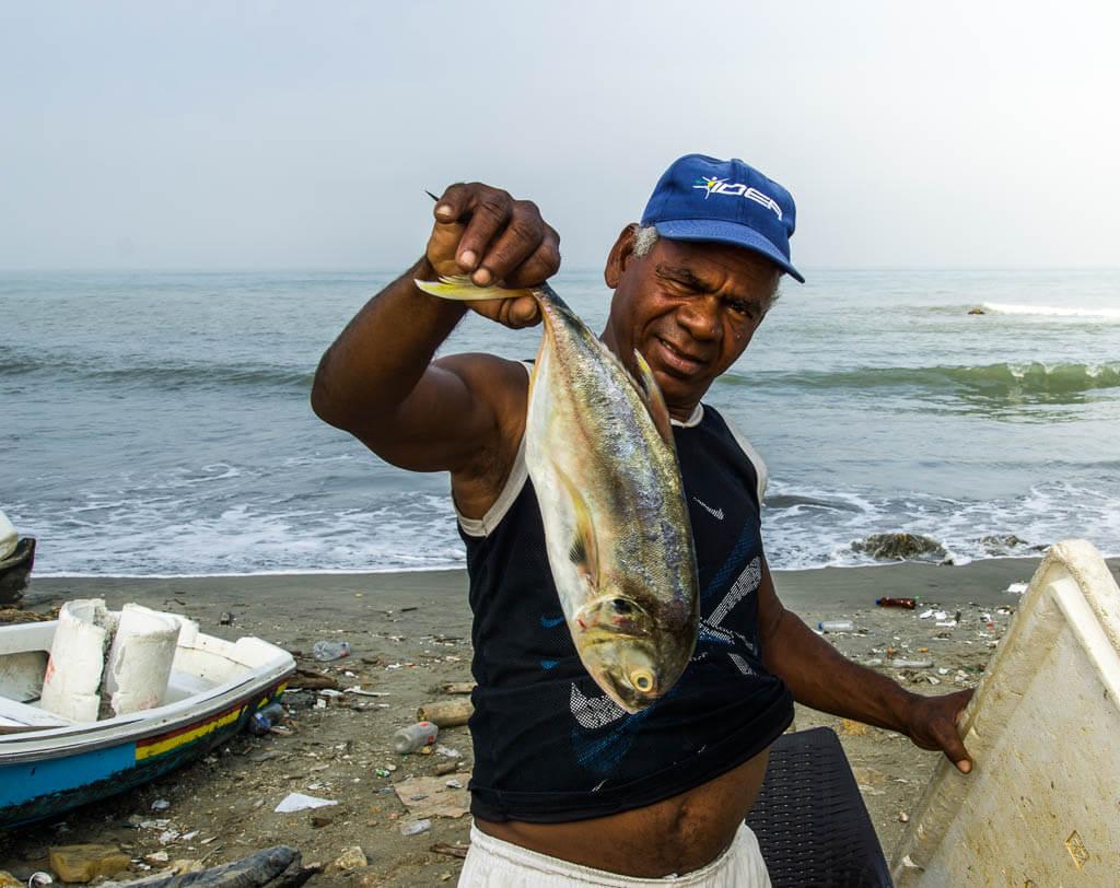 Fisherman in ball cap holding up a fish