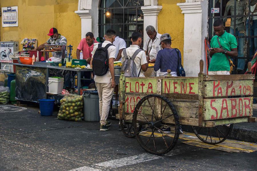 Things to do in Cartagena:People lined up at a street stall for juice. Green oranges waiting to be squeezed with an empty cart nearby