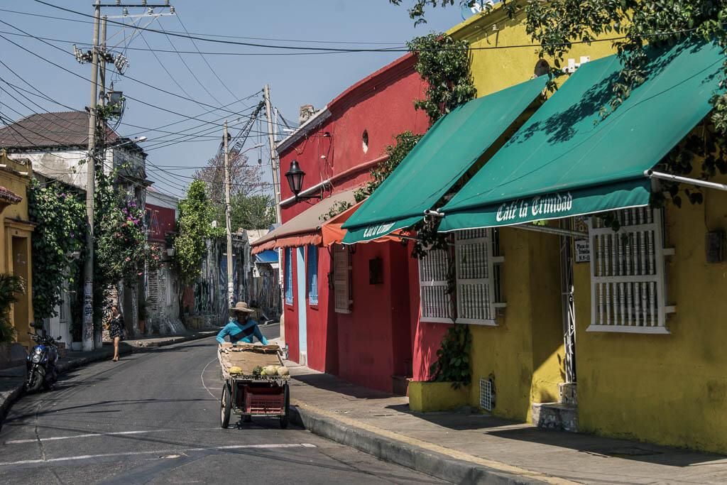Things to do in Cartagena: see colourful houses and a man pushing a cart of fruit