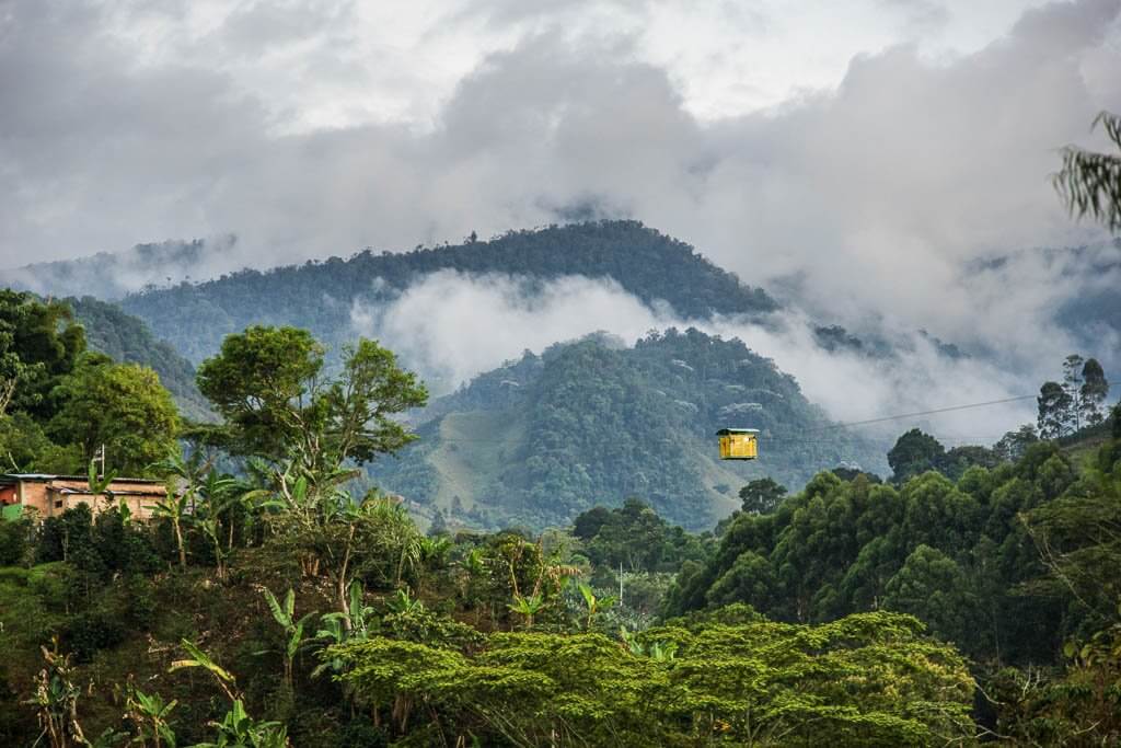 South America Itinerary: Yellow cable car in front of the Andes and clouds rising from the mountains in Jardin Colombia