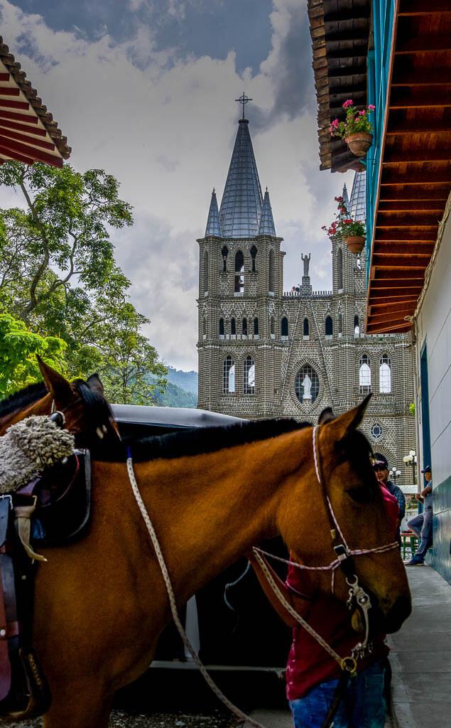 Jardin Colombia:chestnut horse waiting with the church in the background
