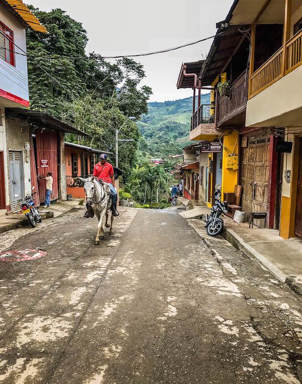 Jardin Colombia: Man in red shirt riding into town on white horse