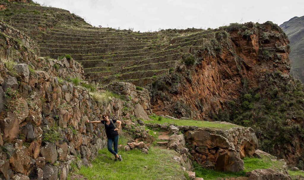 Lone traveller | woman leaning into the cliff at Pisac Peru; terraces in the background