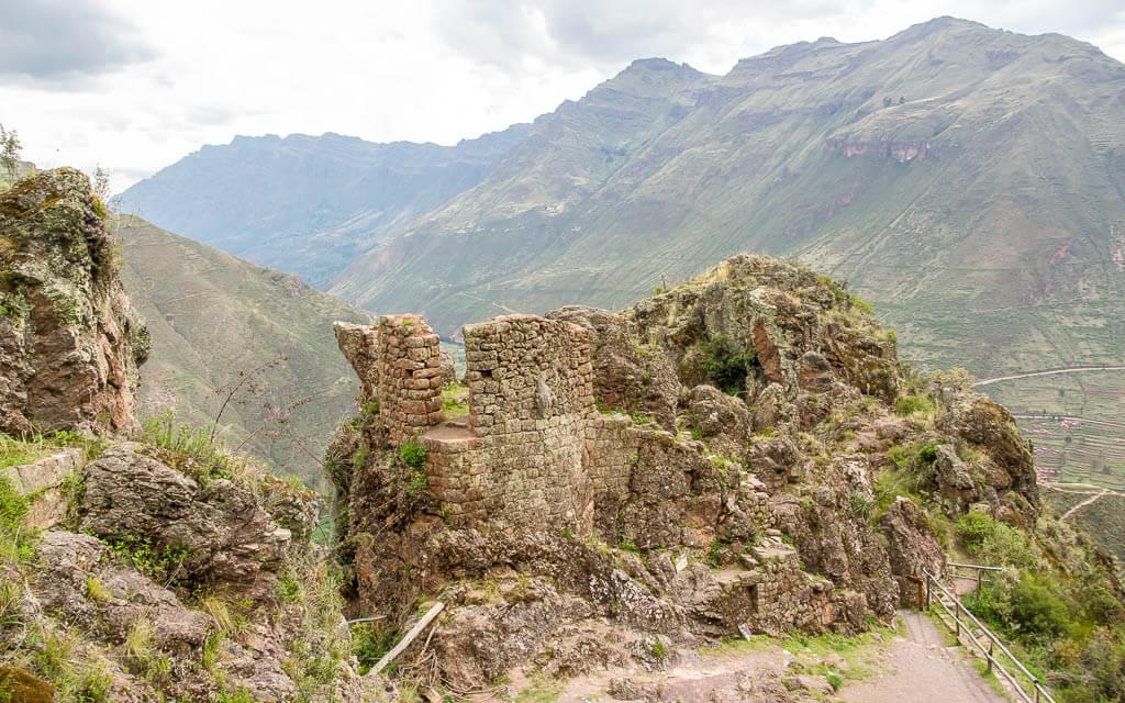 Reddish stone ruins perched with the Andes in the background| Pisac Peru