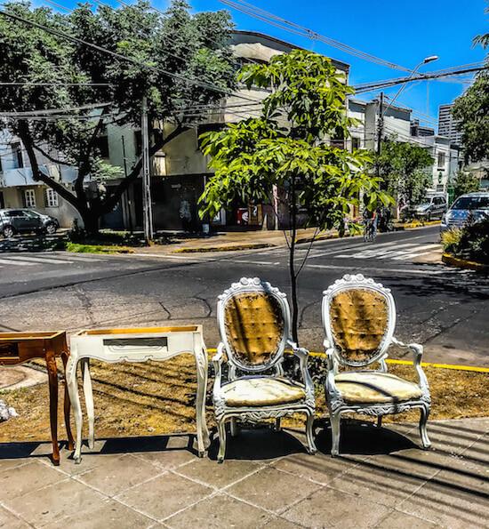 Things to do in Santiago Chile | Barrio Italia with 2 white chairs with golden upholstery and 2 desks on the street corner for sale