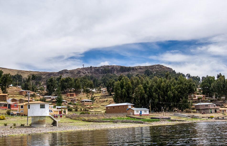 Isla Amantan Peru:approaching shore, houses are scattered up the hillside