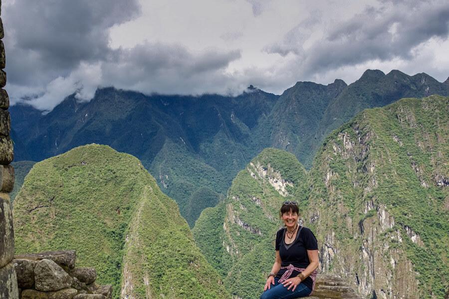 Solo Travel in South America: lady seated, smiling with the moss covered Andes close by in the background