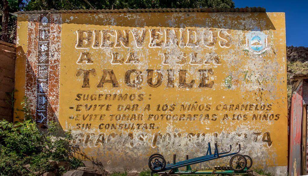Welcome to Taquile Island, a yellow painted and faded sign.
