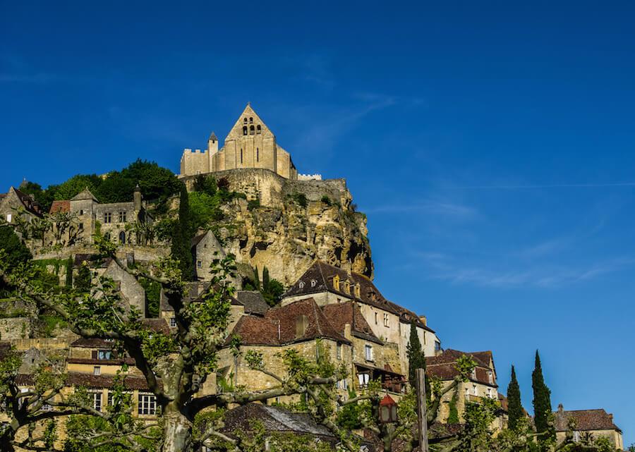 the castle at Beynac perched on a cliff. Blue skies behind