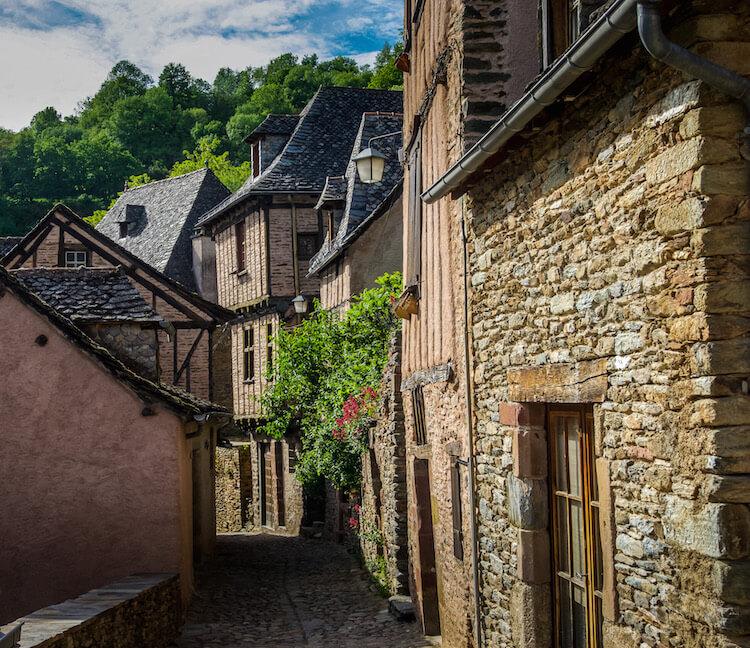 Conques, France: a little cobbled street lined with stone houses and flowers
