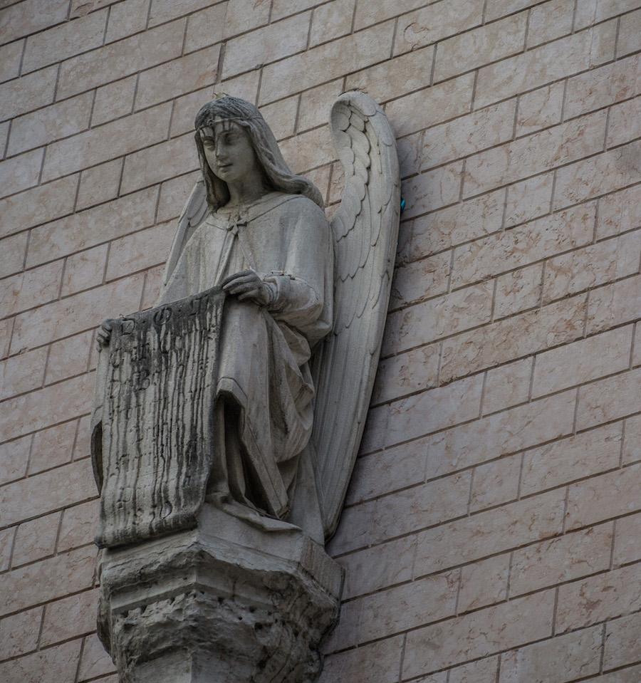 Things to do in Trento Italy: look for the angel statues. Angel looking down holding a scroll