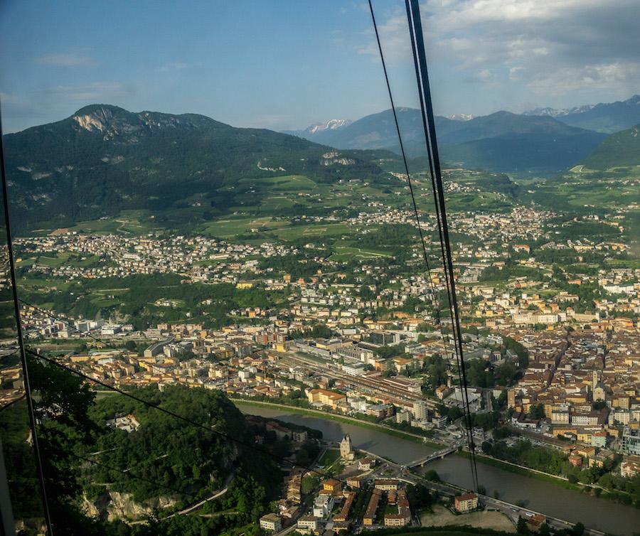  the cable car wires stretch up, the view over trento and the Dolomites behind