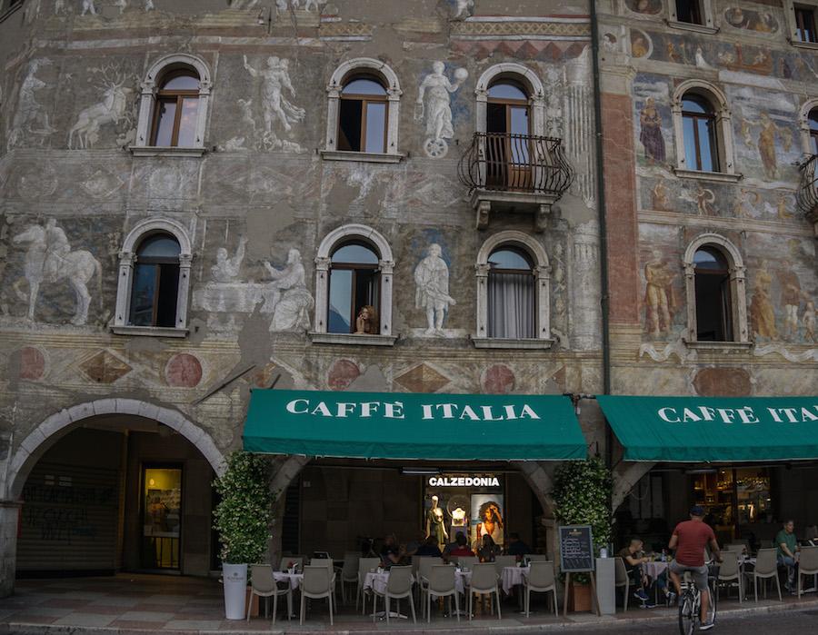 Trento Italy: green awnings that say, Caffe Italia, buildinga above are painted with medieval scenes
