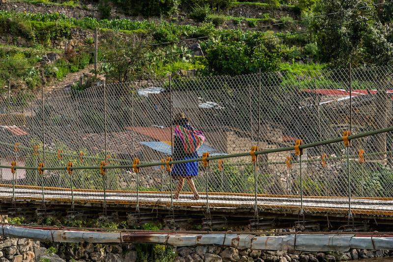 Inca Bridge in Ollantaytambo: Peruvian woman walking across the bridge