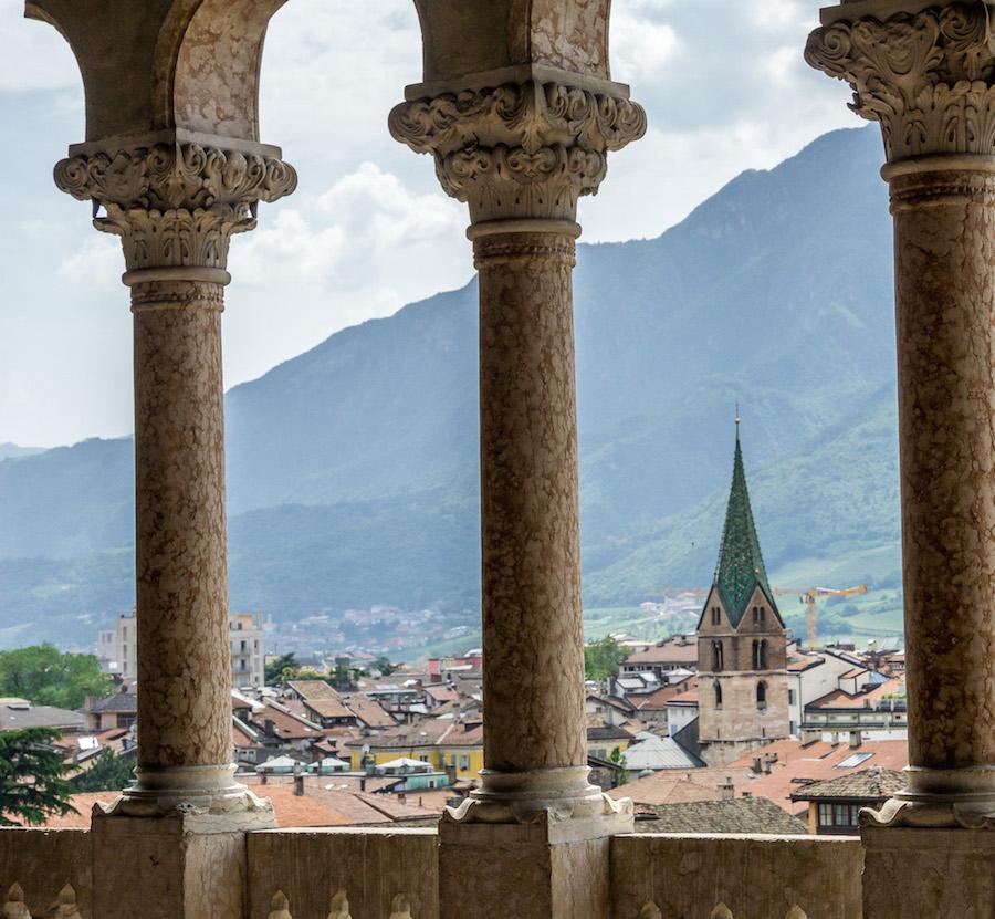 Things to do in Trento Italy: view through pillar over Trento, green spire