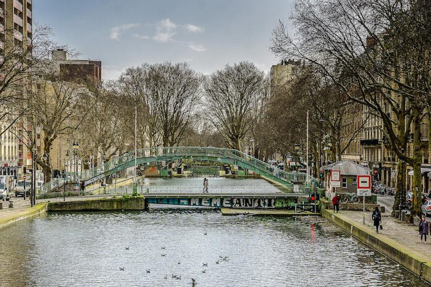 Canal Saint-Martin Paris: bare trees, 2 people walking over the lower bridge with the arched bridge overtop