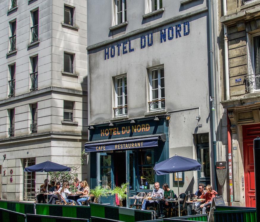 Hotel du Nord - blue awning and blue umbrellas infront of the bar/restaurant where you can take a drink