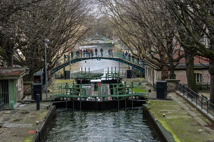 Canal Saint-Martin Paris: people on the bridge watching the swing bridge open and the boat about to go through