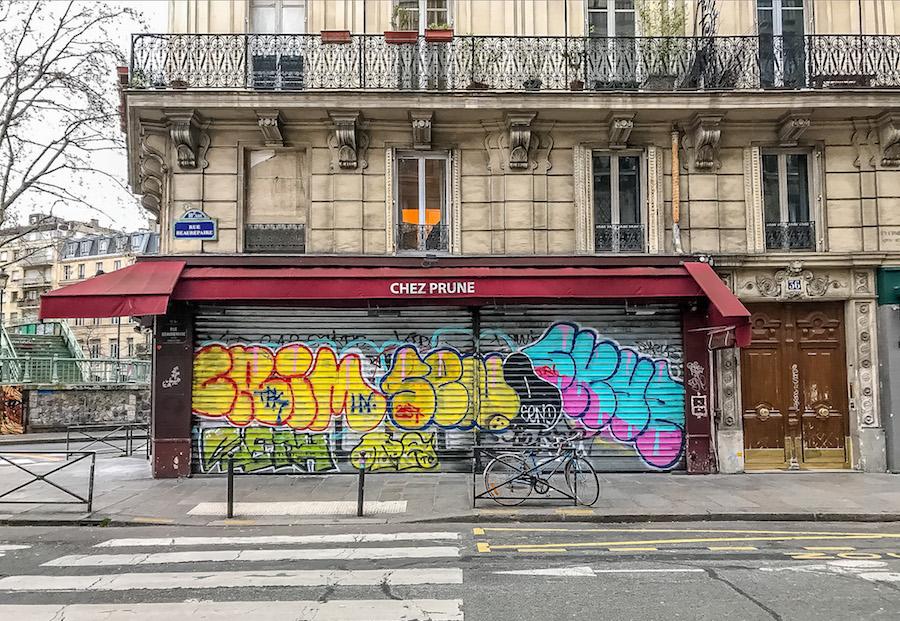 Paris during Coronavirus: Chez Prune café is closed. The metal shutters are rolled down and covered in graffiti