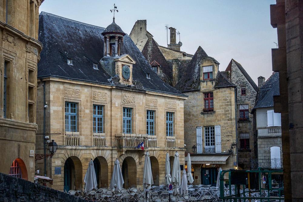 Sarlat in the Dordogne Valley has beautiful stone buildings, these with blue windows and a terrace with the umbrellas down. 