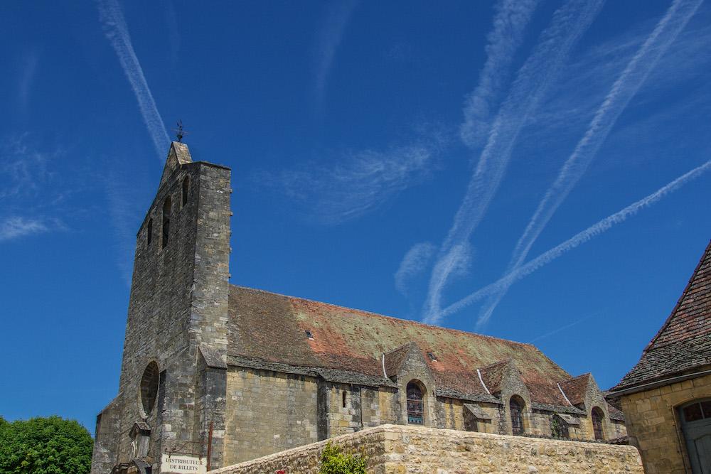 simple church of Domme with blue sky and white streaks of cloud