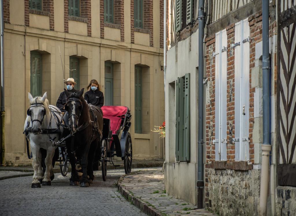 Horse and buggy in Honfleur with the 2 drivers wearing blue masks 